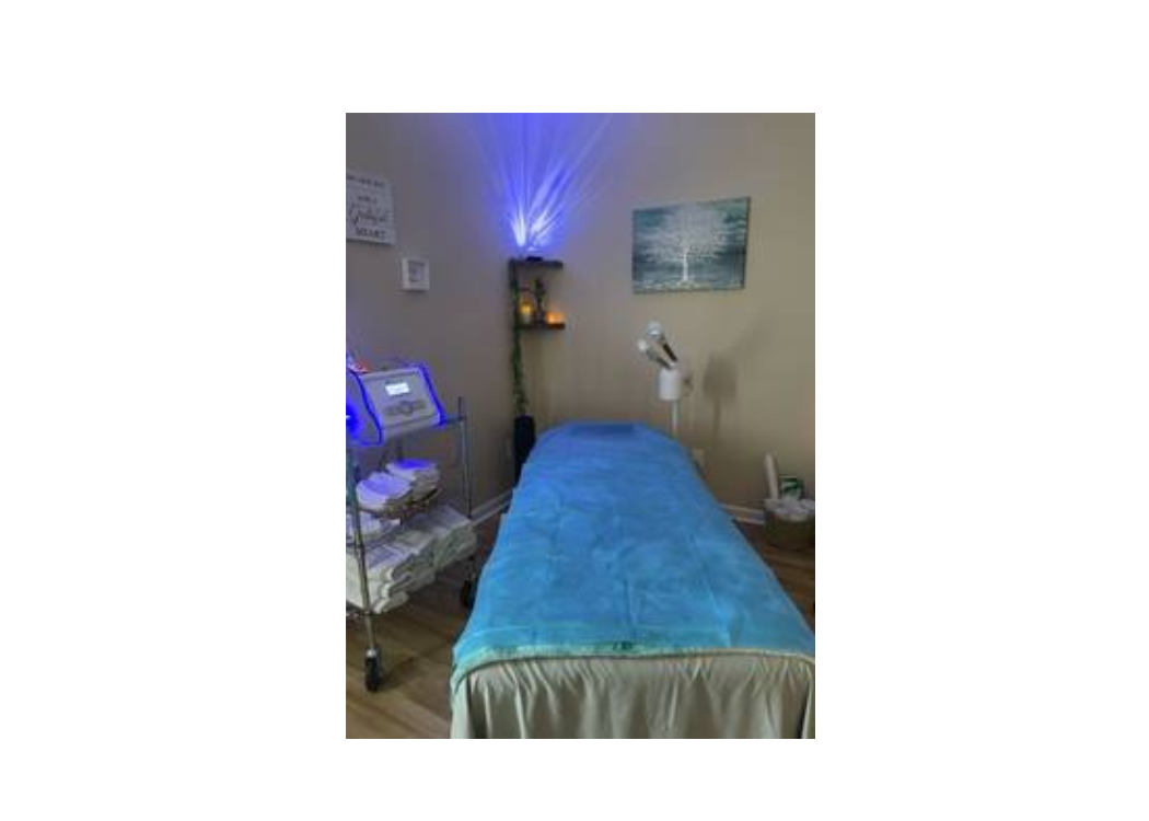 A tranquil massage room illuminated by blue lights, featuring a cozy blue blanket on the treatment table.
