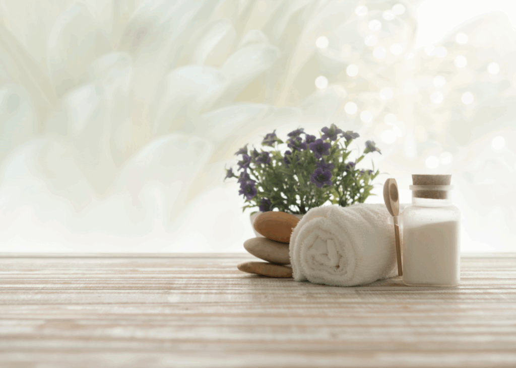 Spa products arranged on a wooden table, featuring flowers and a bottle of soap for a relaxing atmosphere.